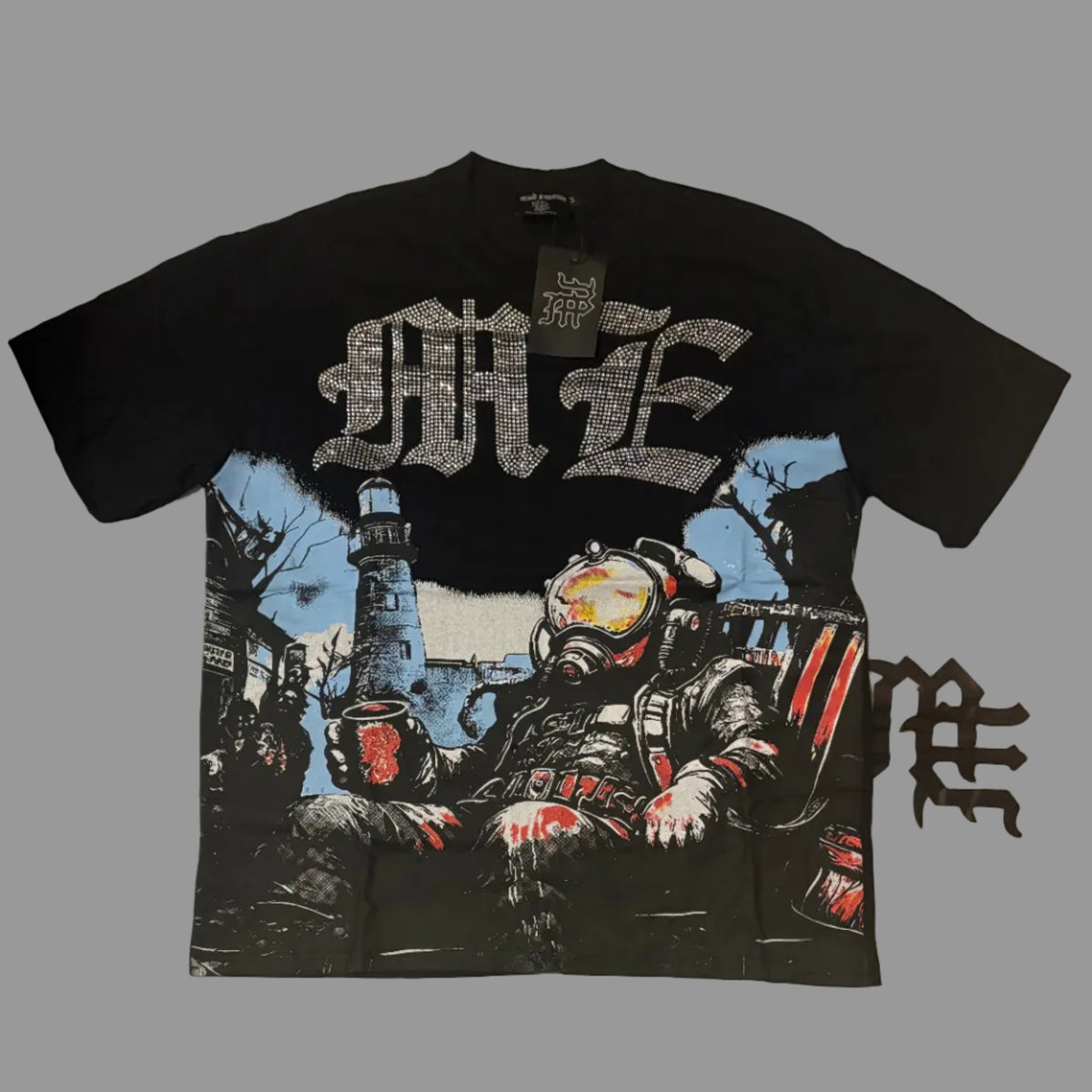 A black short-sleeve graphic t-shirt laid flat on a white wrinkled surface. The shirt features a large silver gothic-style logo on the chest, a detailed graphic of a character in a hazmat suit below, and a small black gothic logo on the right sleeve.